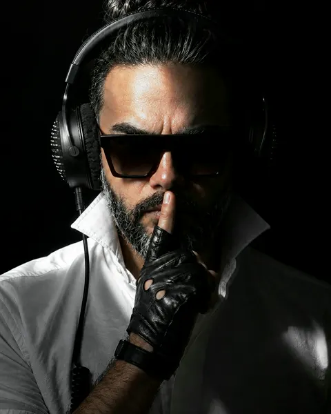 A plain photo of a DJ in headphones and sunglasses
